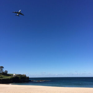 View from beach with plane taking off in the distance